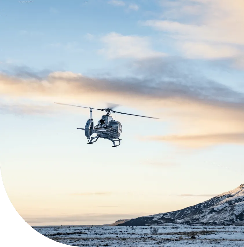 Helicopter flying across a sunset sky