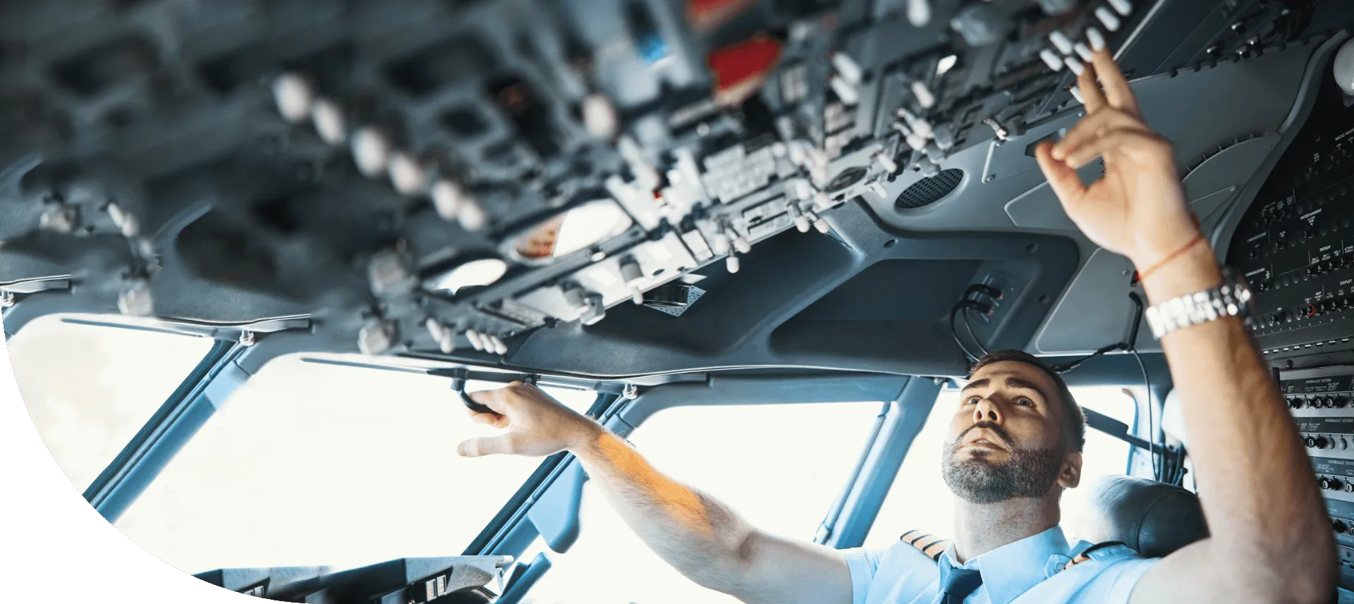 Pilot reaching up to the overhead switch panel in an airliner cockpit