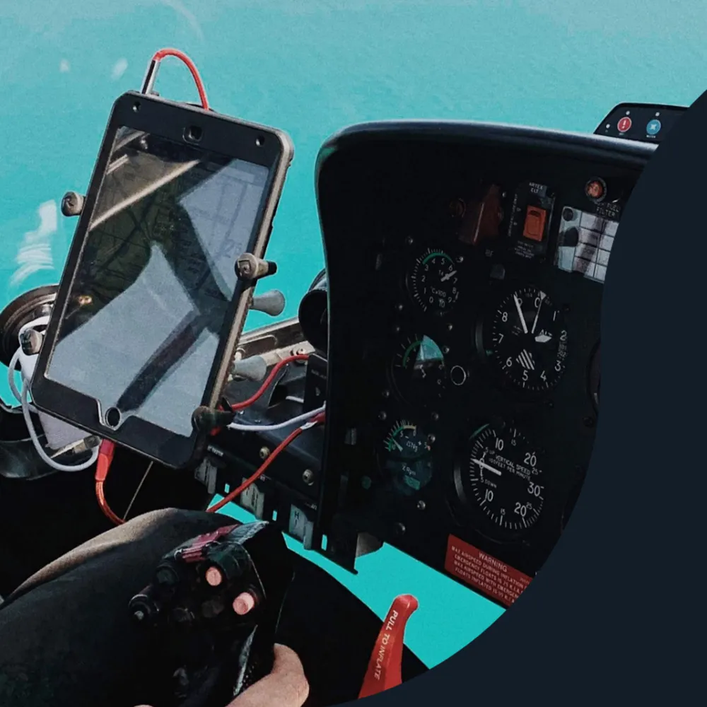 Pilot’s hand on the controls beside a tablet mounted in a helicopter cockpit