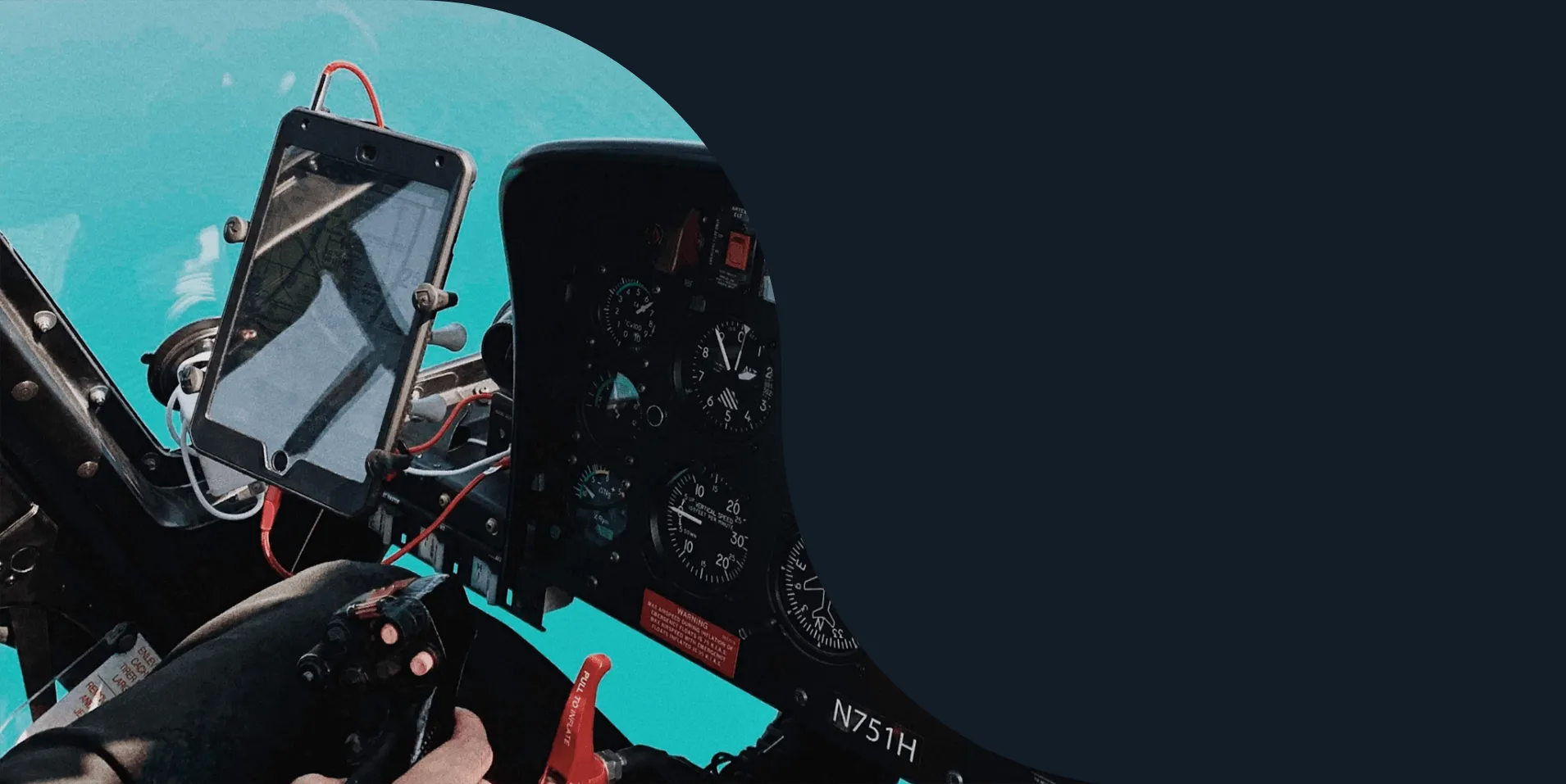 Pilot’s hand on the controls beside a tablet mounted in a helicopter cockpit