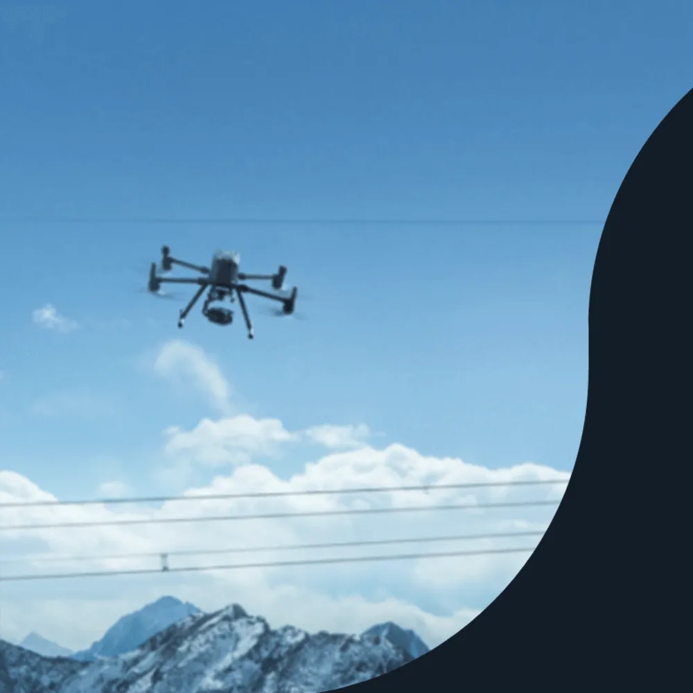 Hexacopter drone flying above power lines with snowy mountains behind