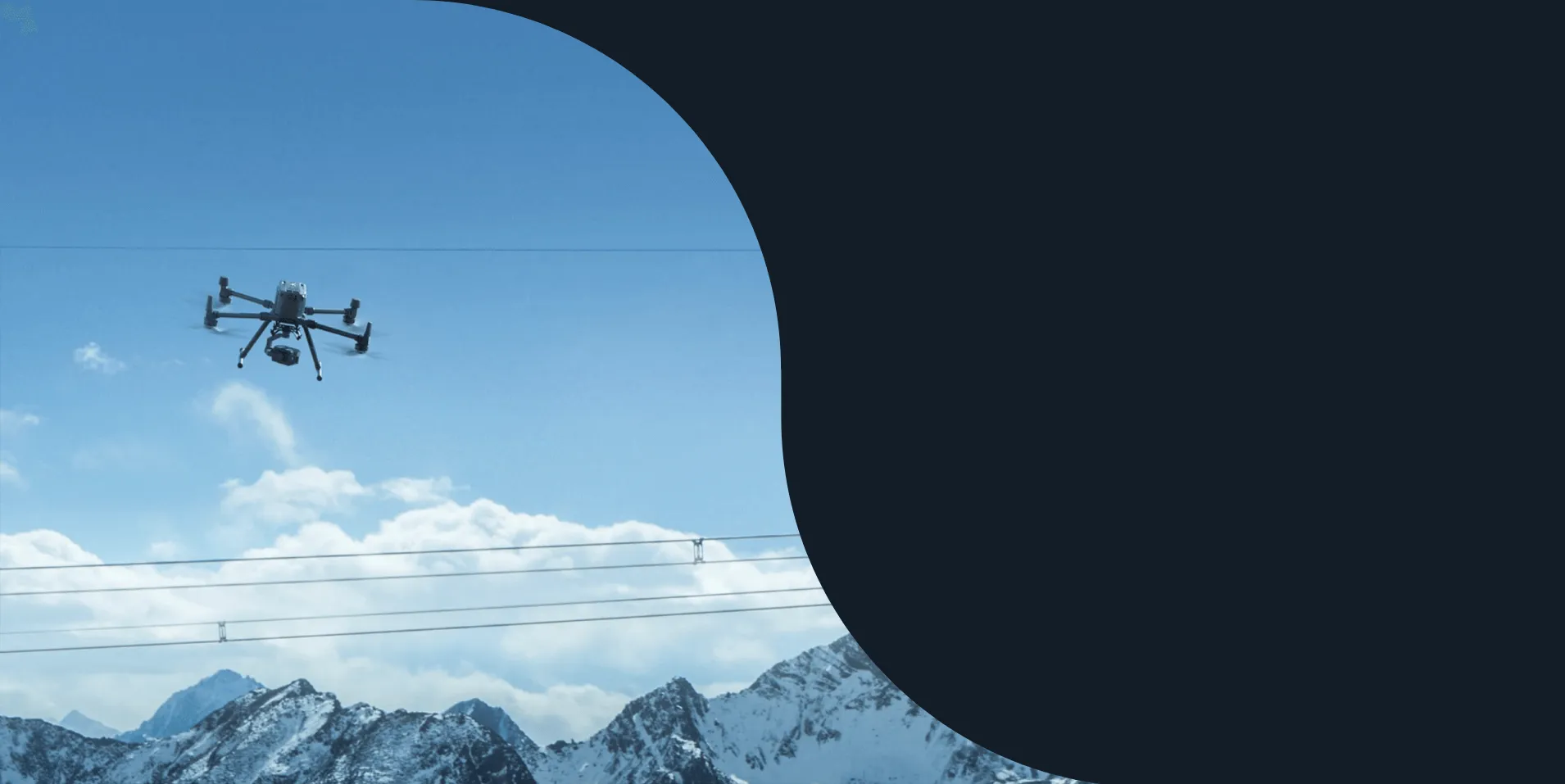 Hexacopter drone flying above power lines with snowy mountains behind